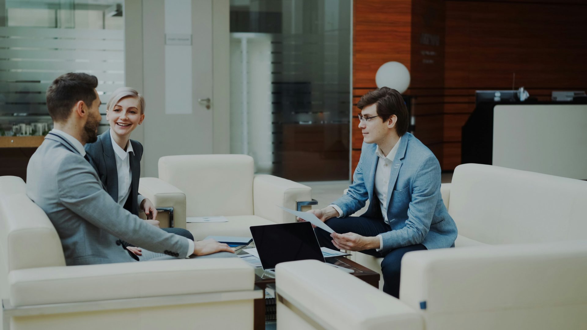 Three professionals in a modern office lounge.